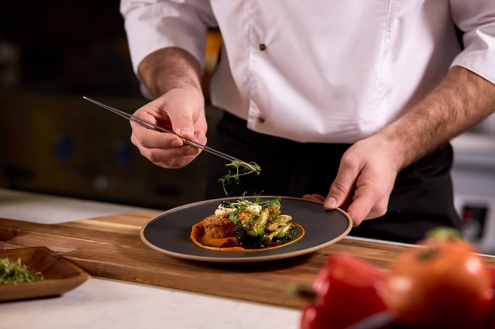 Chef dressing salad with fresh greens