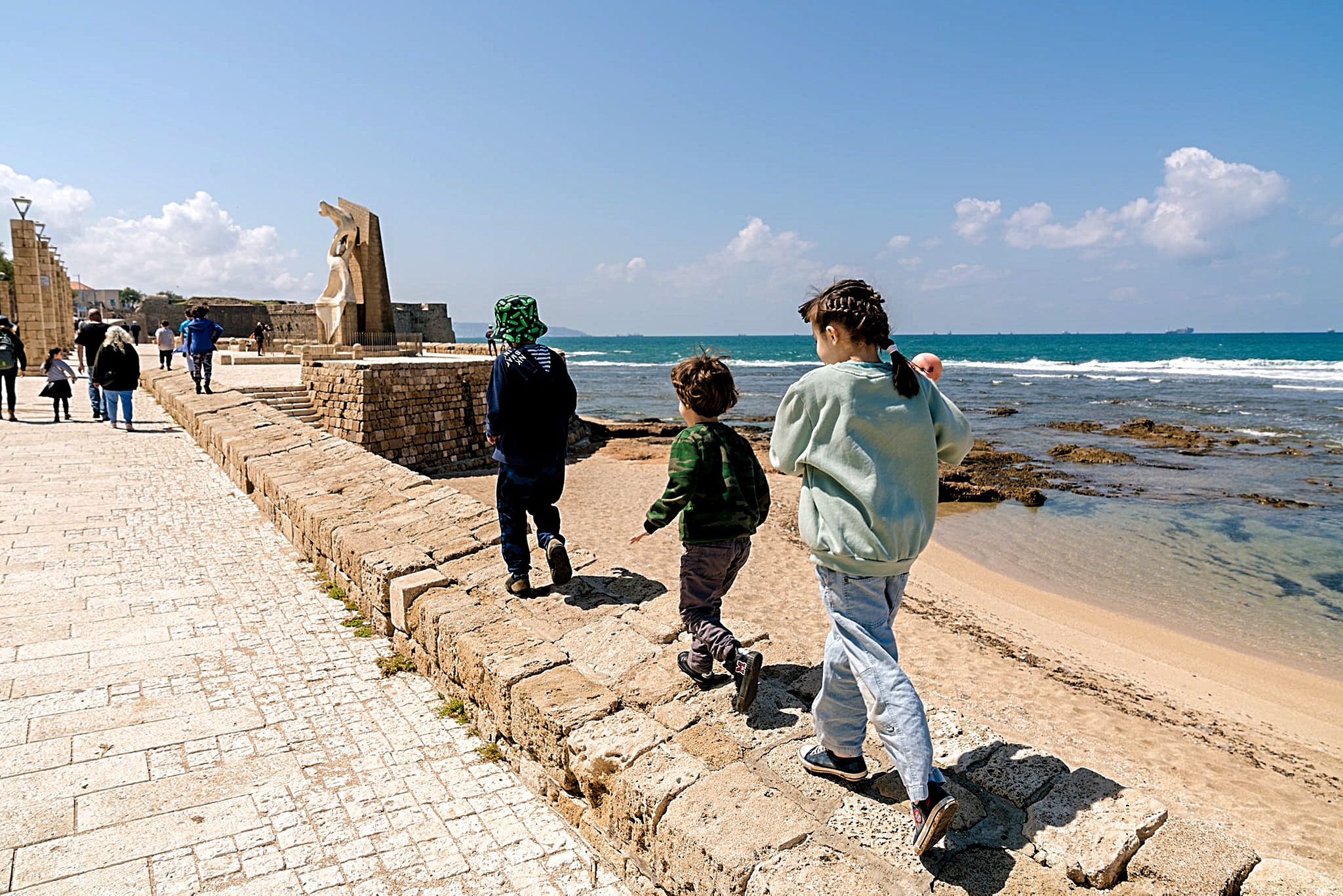 Children walking by the sea in Acre, Israel