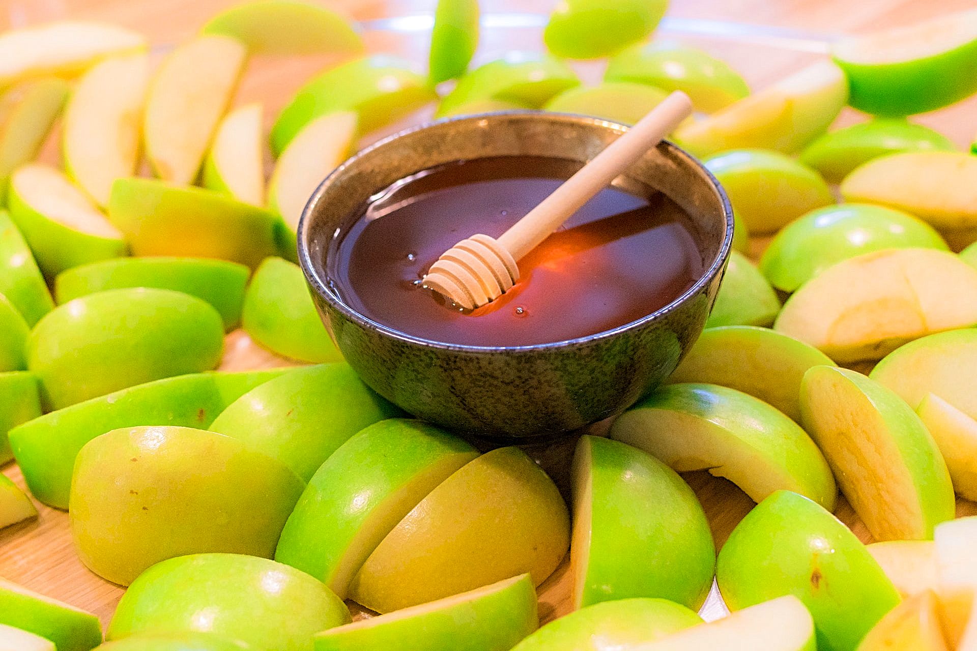 Rosh Hashanah honey bowl with a wooden honey dipper and apples