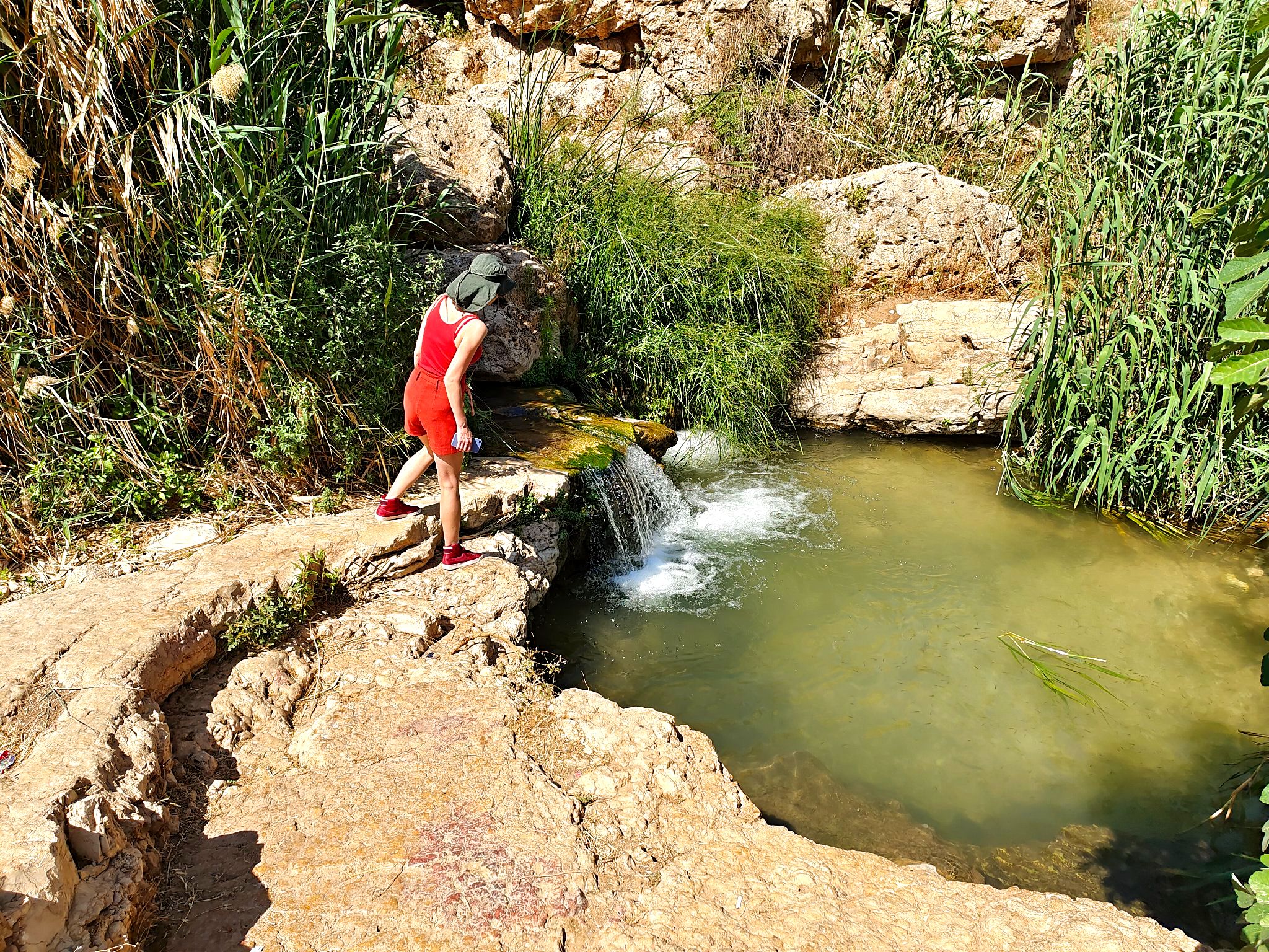 Tourist approaching a small waterfall in Ein Prat, Israel
