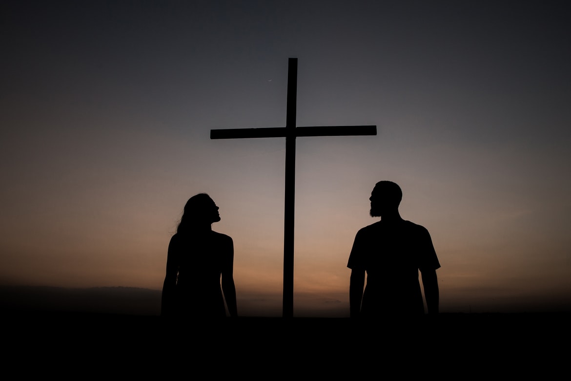 Silhouettes of man and woman near a cross