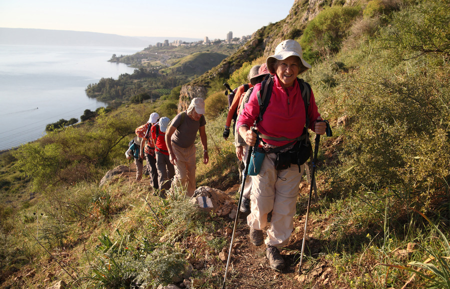 Hikers climbing Mt. Arbel with Tiberias seen far in the back